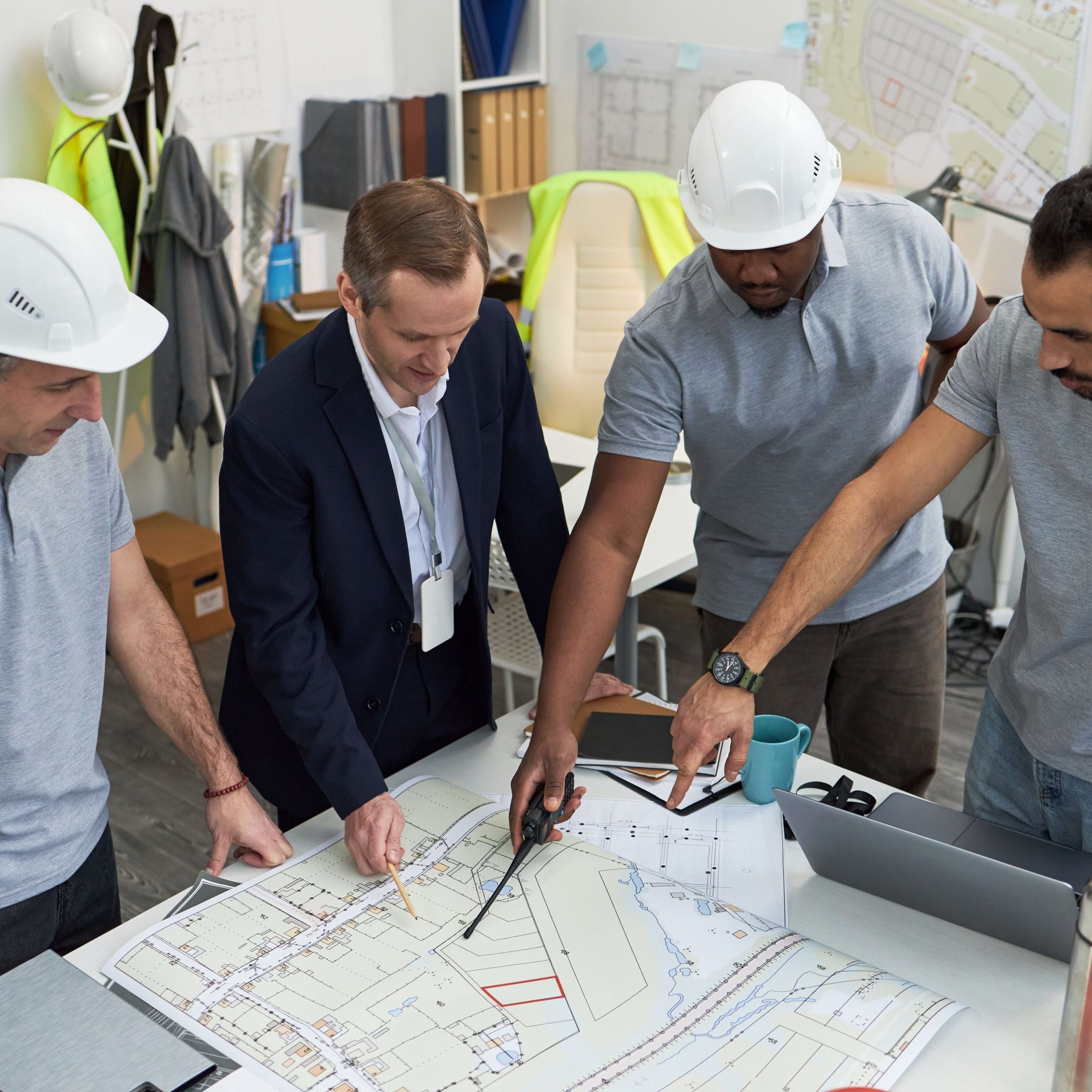 Middle Aged Caucasian Foreman Supervising Multiethnic Team Reviewing Blueprints